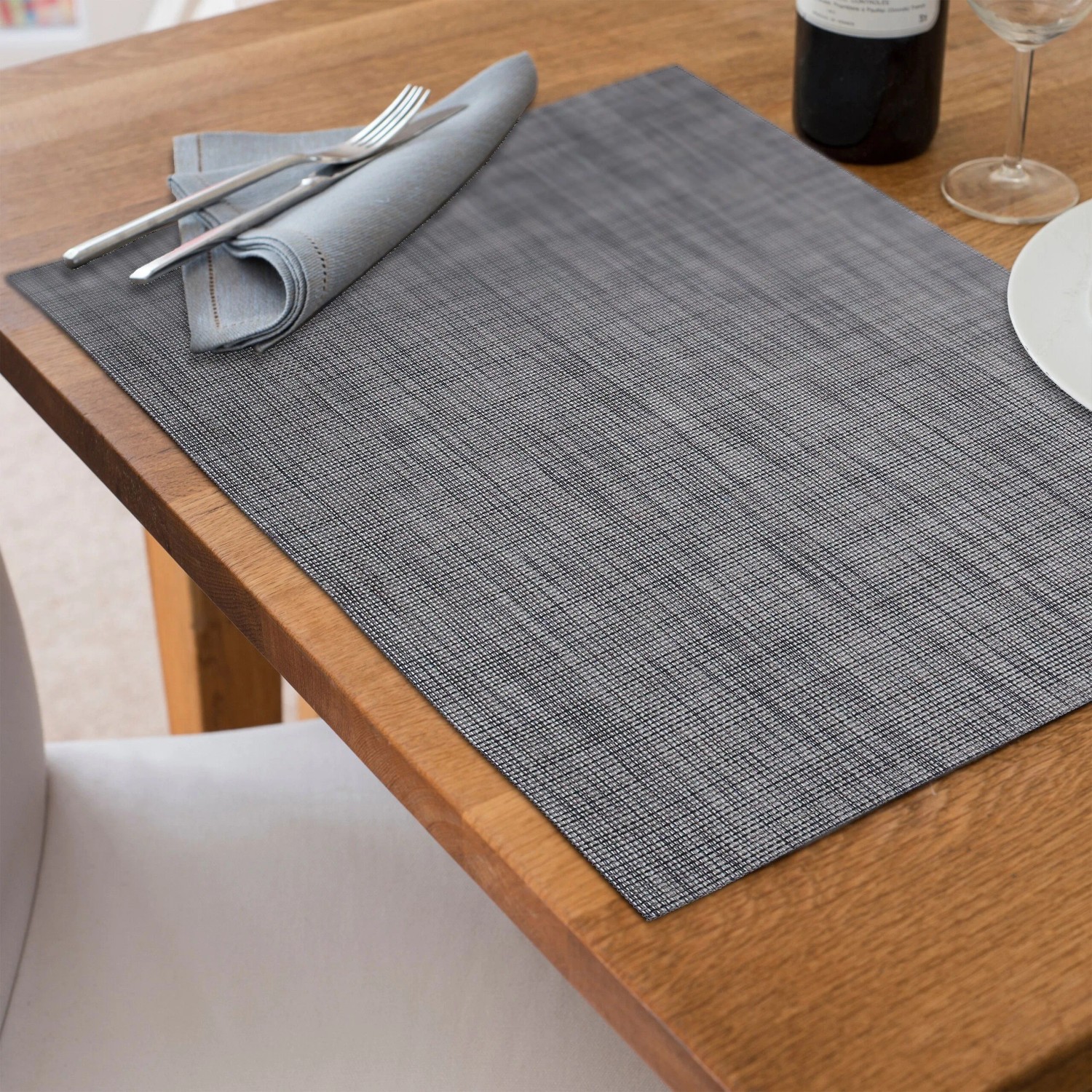 Graues, rechteckiges Tischset aus Polyester/PVC mit gewebter Struktur auf Holztisch, für Esstisch. Abwaschbar.