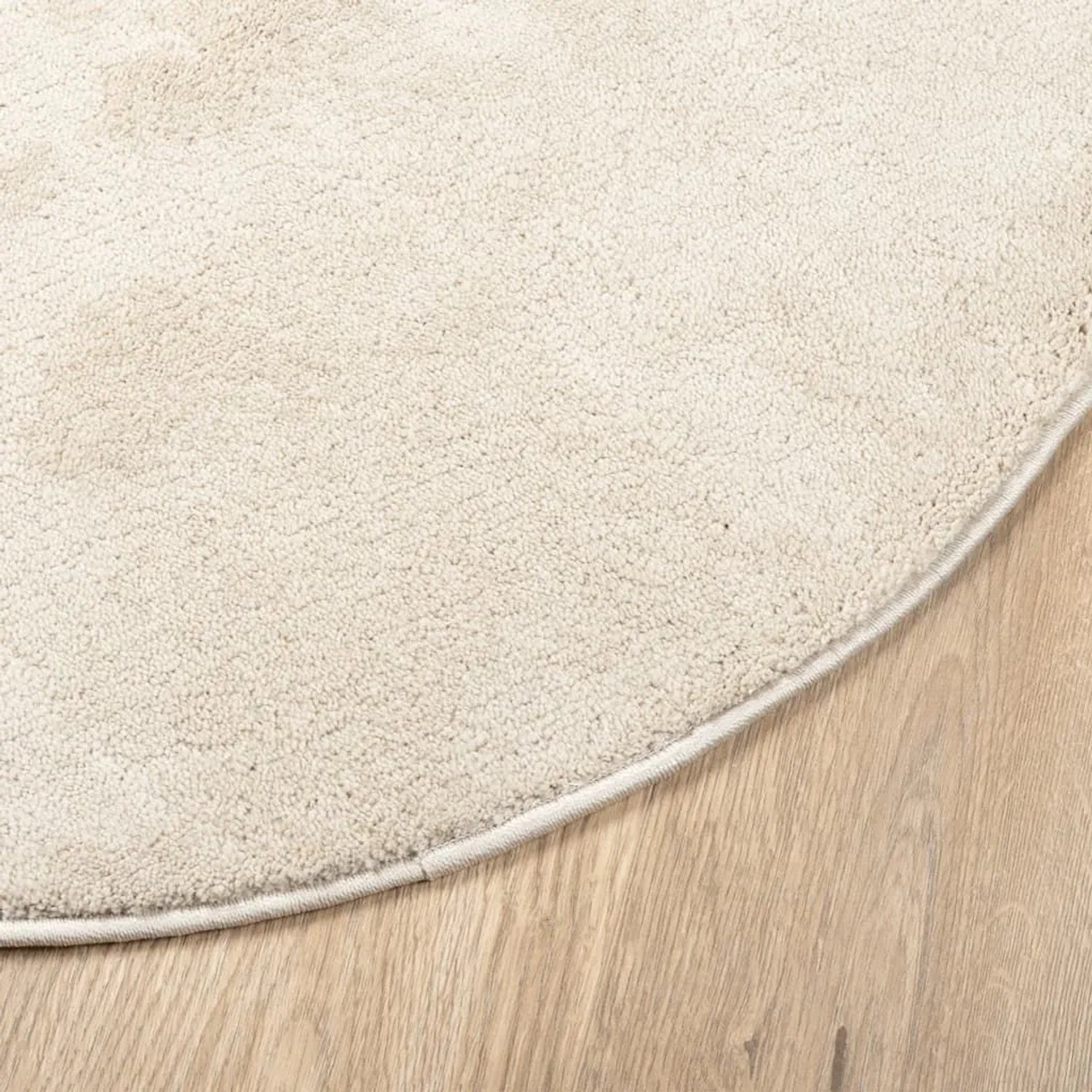 Beiger runder Kurzflor-Teppich OVIEDO auf Holzfußboden. Weiche, dichte Textur, Ø 120 cm.
