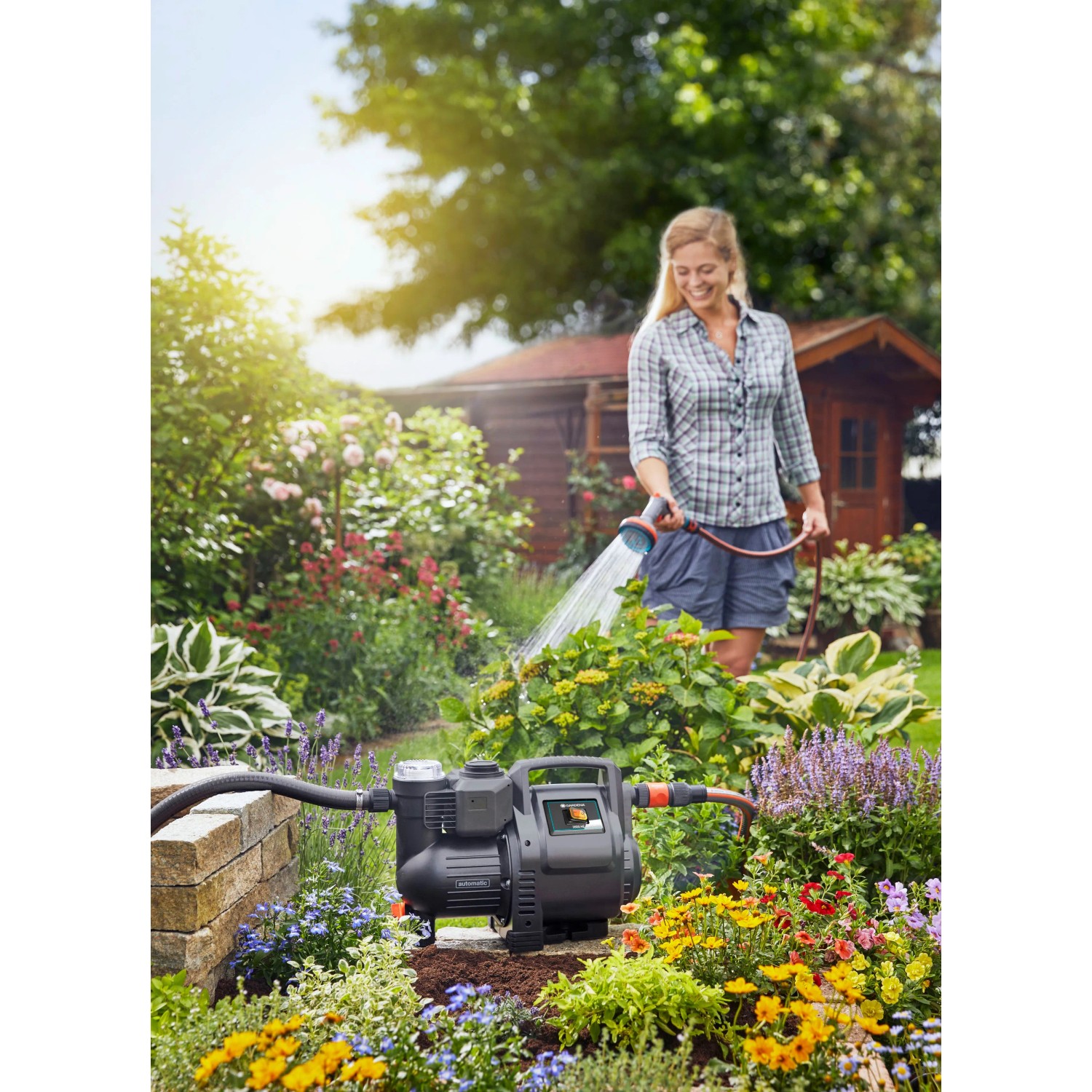 Gardena Haus- und Gartenautomat 3500/4 im Einsatz: Frau bewässert Garten mit Elektro-Pumpe.