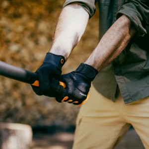Hände mit Fiskars Axt- und Werkzeug-Handschuhen (Größe 12) in Schwarz-Orange halten einen Werkzeugstiel.