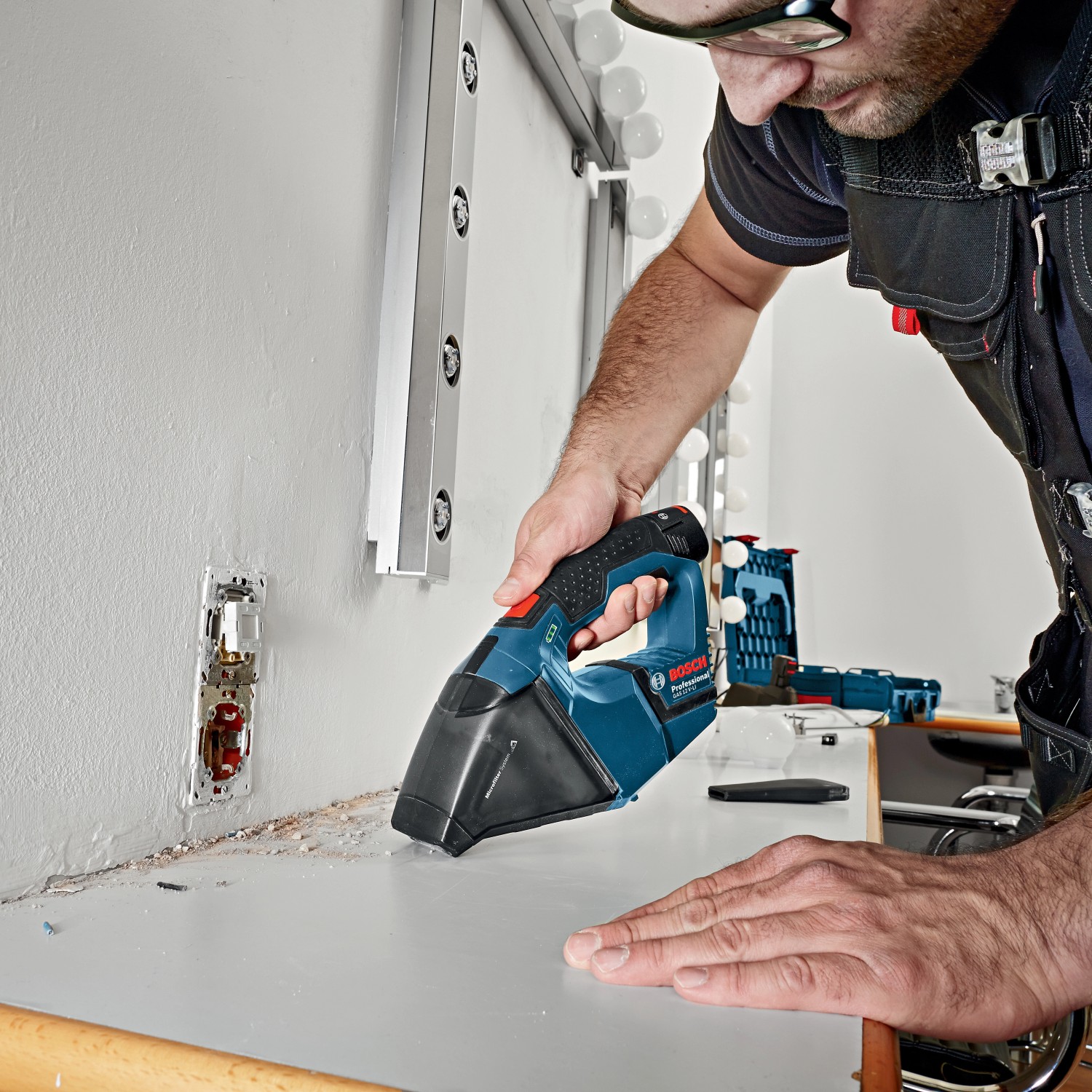 Bosch Professional Akku-Handstaubsauger GAS 12 V-LI im Einsatz beim Reinigen einer Werkbank.