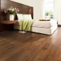 Verlegter Laminatboden Comfort Pinie Mokka Dunkel 7 mm im Schlafzimmer mit Bett und Fenster.