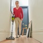 Frau saugt mit dem Ryobi Akku-Staubsauger RSVS18-0 One+ 18V den Flur.