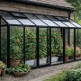 Schwarzes Aluminium-Wandgewächshaus GHLT11 mit 4mm Glas an Holzwand. Tomatenpflanzen innen, Lüftungsfenster offen. Garten.