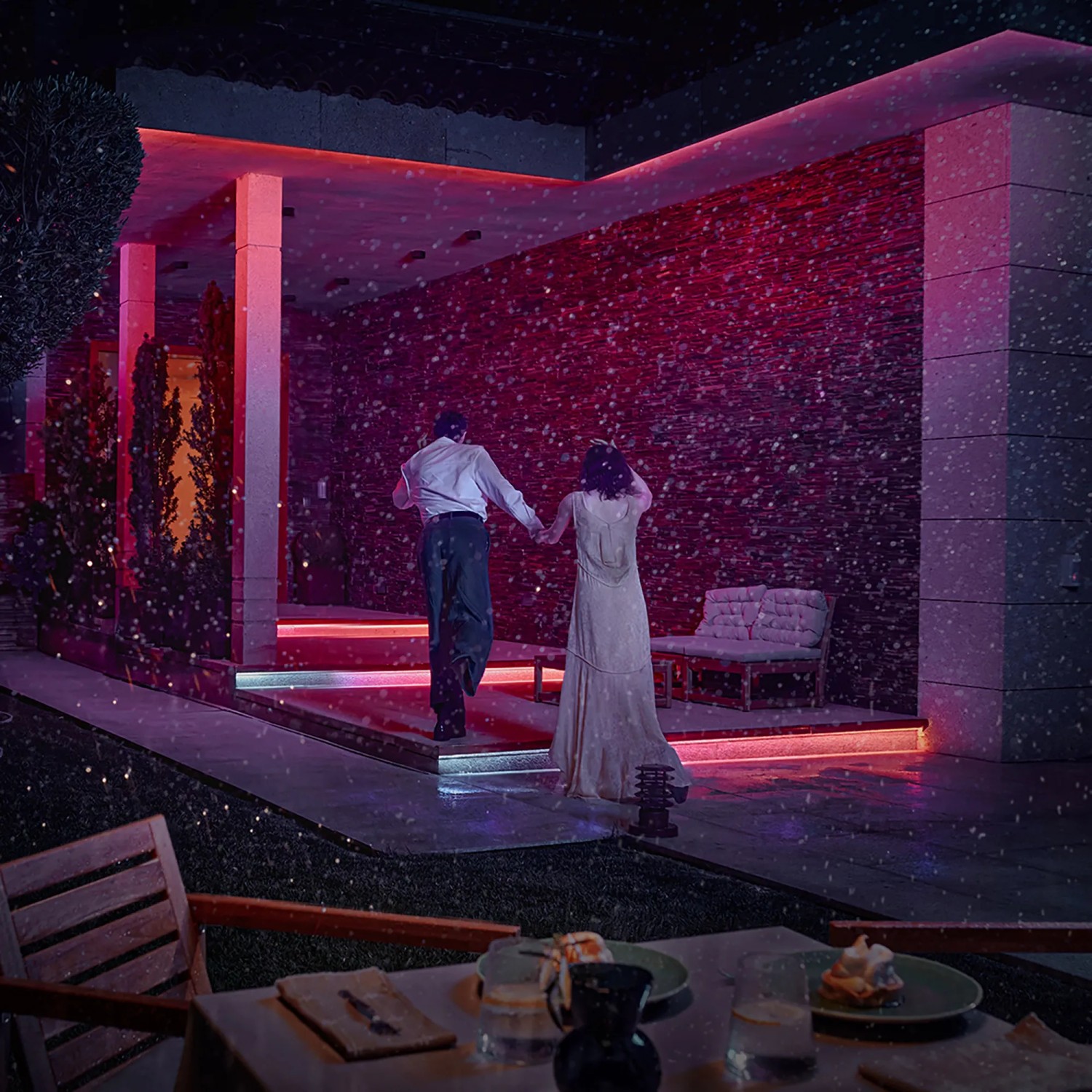Paar unter Philips Hue Outdoor Lightstrip, farbiger Fassade und Gartenbeleuchtung.
