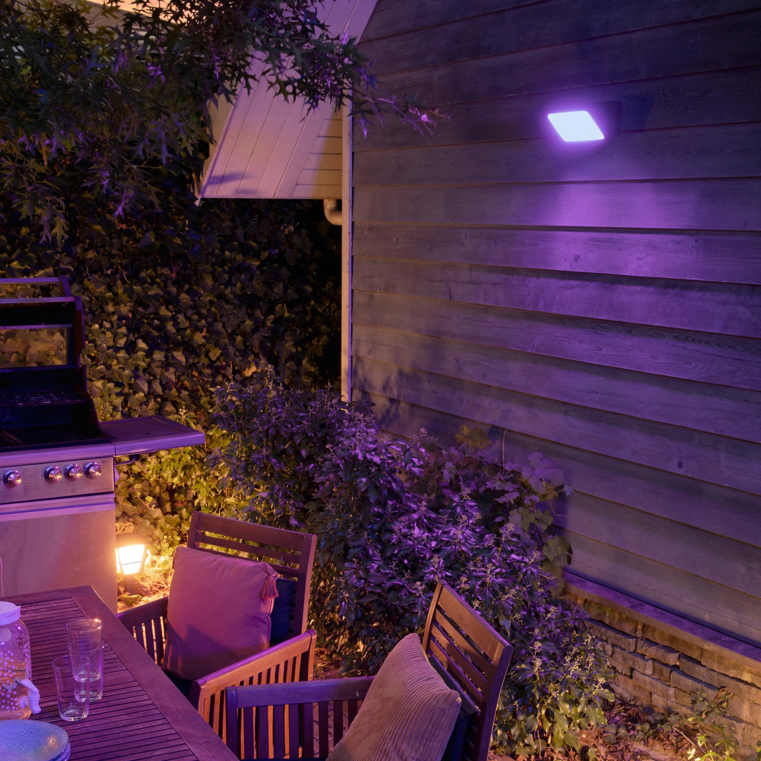 Philips Hue Discover: LED-Wandlampe mit Farbwechsel beleuchtet Garten und Terrasse in Lila.