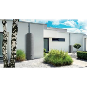Arves Regenwassertank Novara 500 l, schwarz, im Garten mit Hauswand und Bepflanzung.