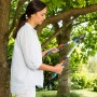 Frau schneidet mit der Gardena TeleCut Astschere Äste an einem Baum im Garten.