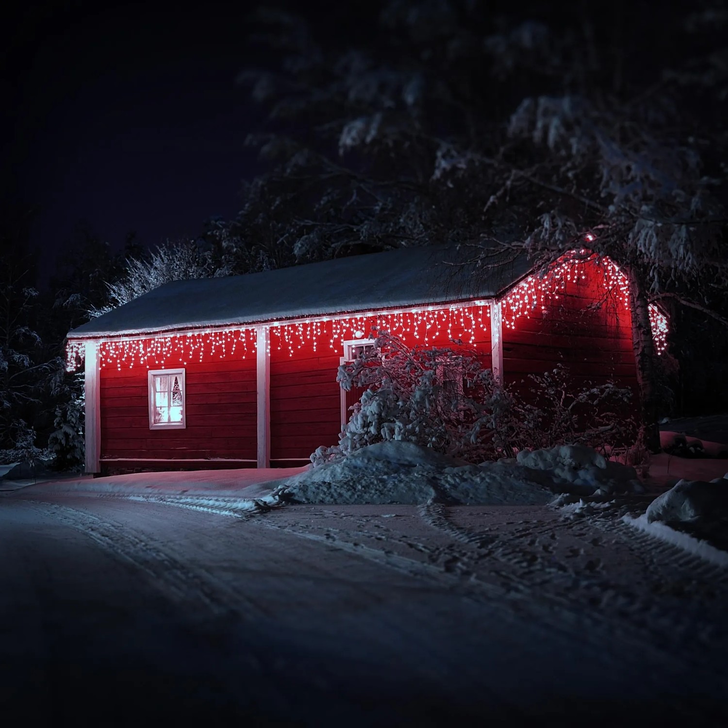 Rote Scheune im Schnee mit kaltweißem LED Lichtervorhang (6m, 180 LEDs) als Weihnachtsbeleuchtung.