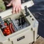 Geöffnete Petromax Kühlbox kx25 in Sand, gefüllt mit Eis, Getränken und Lebensmitteln.