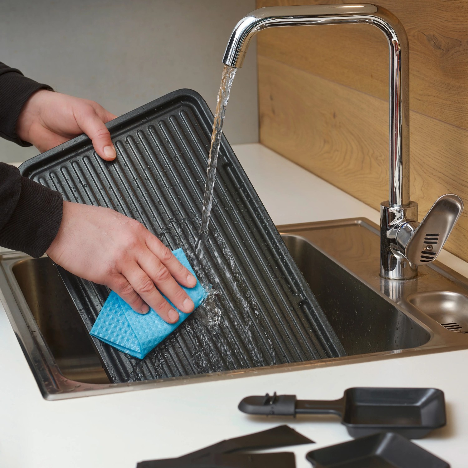 Reinigung der Grillplatte eines Severin Raclette-Grills RG 9670 in der Spüle.