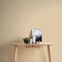 Beige-gelbe, matte Vliestapete Uni Glatt FSC® an Wand hinter Tisch mit Deko.
