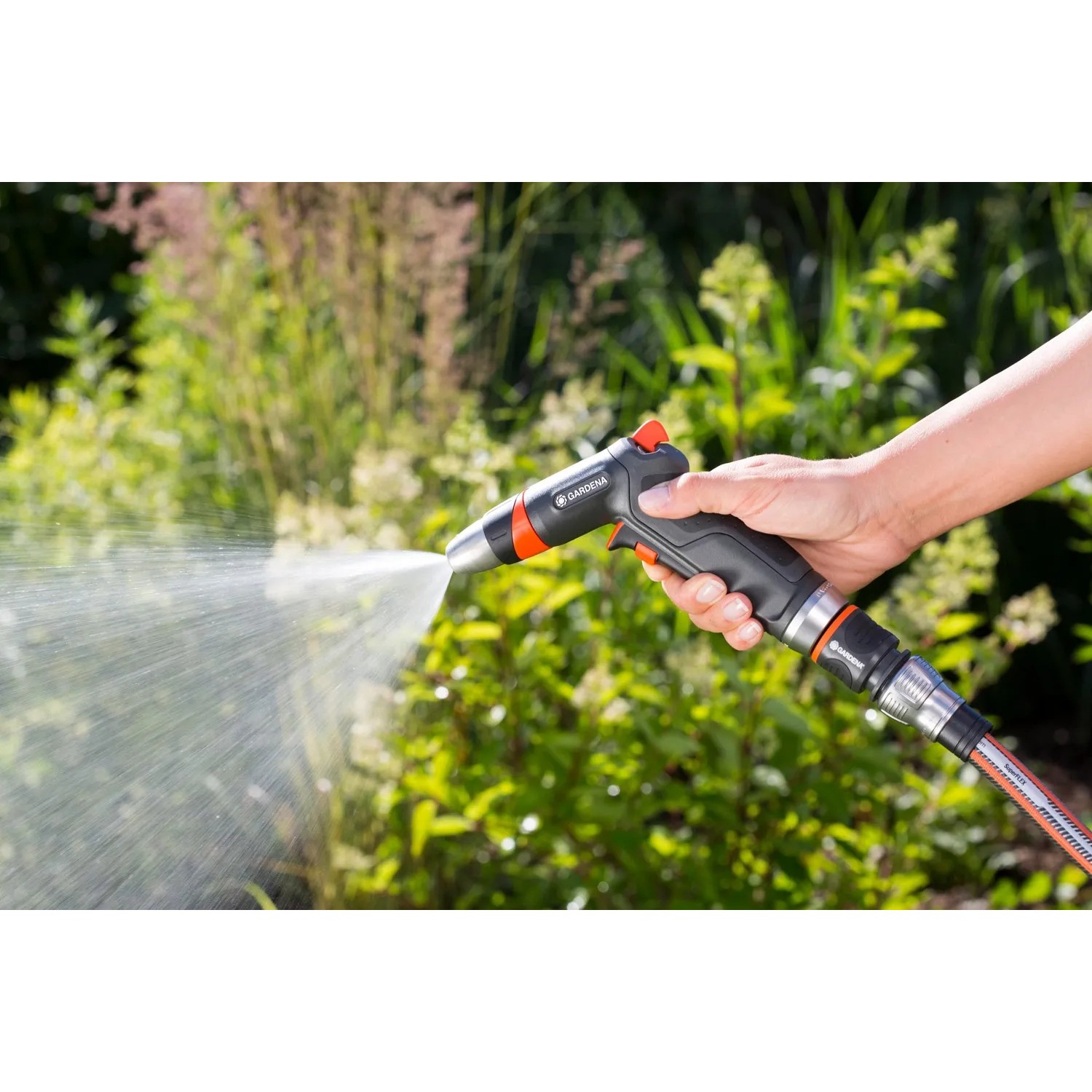 Gardena Premium Reinigungsspritzen-Set im Einsatz: Hand hält Spritze, Wasserstrahl ist sichtbar.