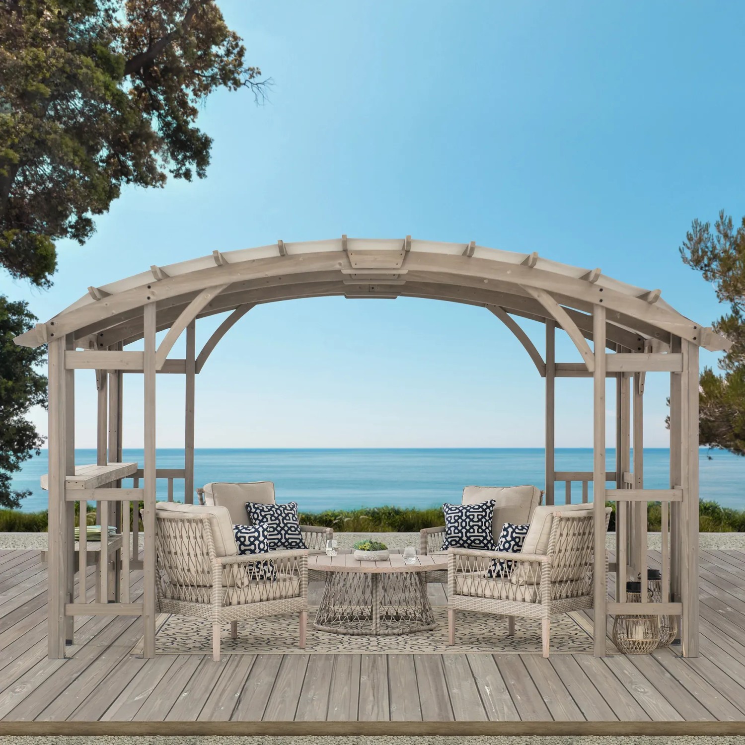 Graue Sunjoy Pergola Dajti aus Zedernholz (427x305cm) mit Möbeln auf einer Terrasse mit Meerblick.