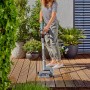 Frau reinigt Terrasse mit Gardena Akku-Multi-Reiniger AquaBrush Patio inkl. Akku.