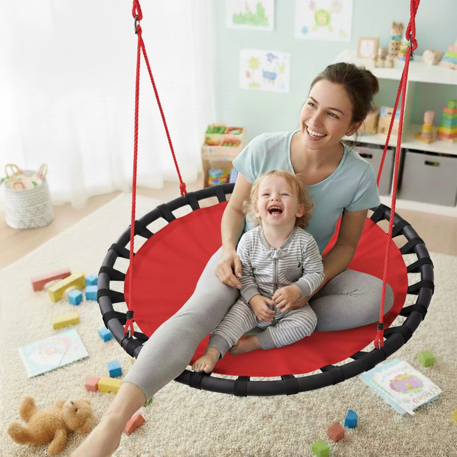 Lachende Mutter und Kind auf roter Relaxdays Nestschaukel. Höhenverstellbare Rundschaukel aus Stoff und Stahl für Spielspaß.