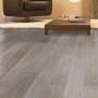 Verlegter Laminatboden Comfort Kiefer Vintage 7 mm im Wohnraum mit Sessel und Tisch.