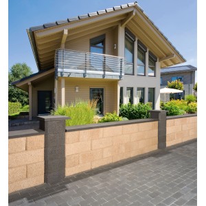 Graue EHL Planomur Mauerabdeckplatte auf einer Gartenmauer vor einem Haus.