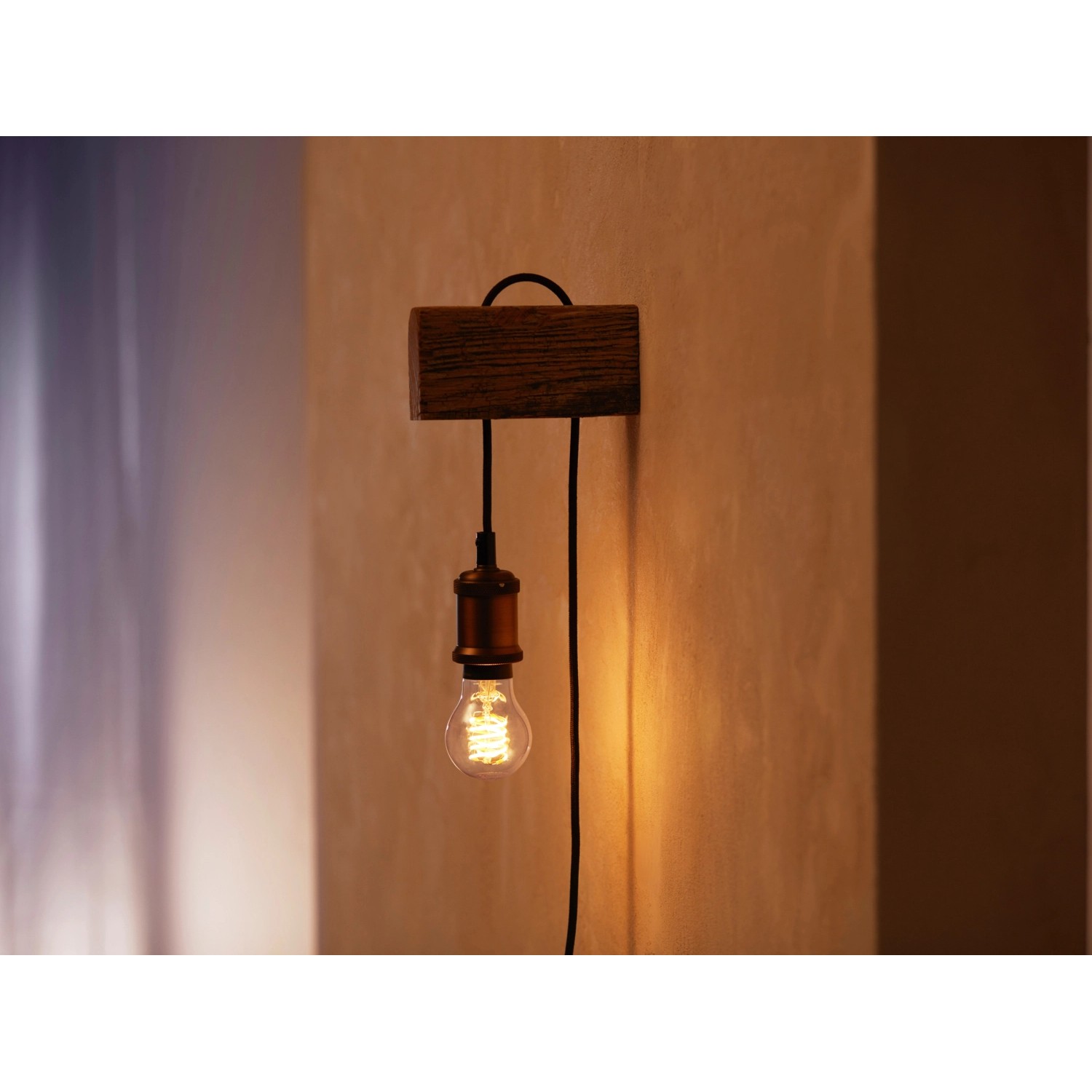 Philips Hue Filament Lampe A60 E27 an Holzhalterung mit Kabel an Wand.