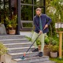 Mann reinigt Treppe mit Gardena Cleansystem Stielbürste Hard Flex in Anthrazit.