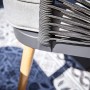 Detailaufnahme Lounge-Sessel Edna: Anthrazitfarbenes Stahlgestell mit Seilbespannung und beiger Auflage.