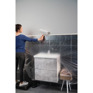 Frau streicht Wand mit Tesa Abdeckfolie Easy Cover Economy XL. Schutz vor Farbspritzern.