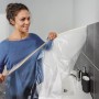 Frau bringt Tesa Abdeckfolie mit Klebeband im Bad an. Schutz vor Farbspritzern bei Renovierung.