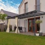 Graue Palram Sierra Terrassenüberdachung (555x295cm) am Haus mit Vorhängen.