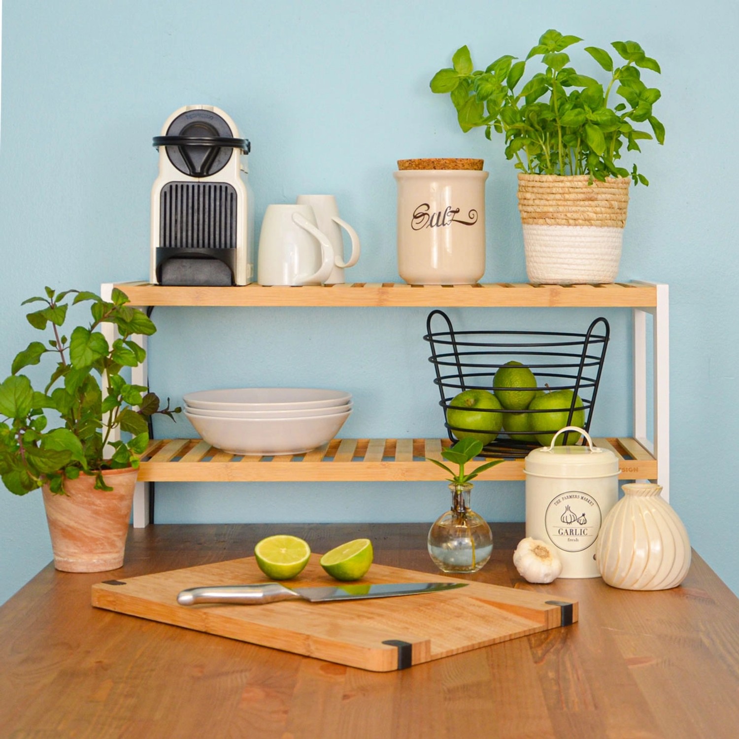 DuneDesign Schuhregal aus Bambus, weiß, mit zwei Ablagen, dekoriert mit Küchenutensilien.