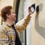 Mann montiert Eufy Solar-Wandleuchte mit Kamera S120 KI 2K an Hauswand.