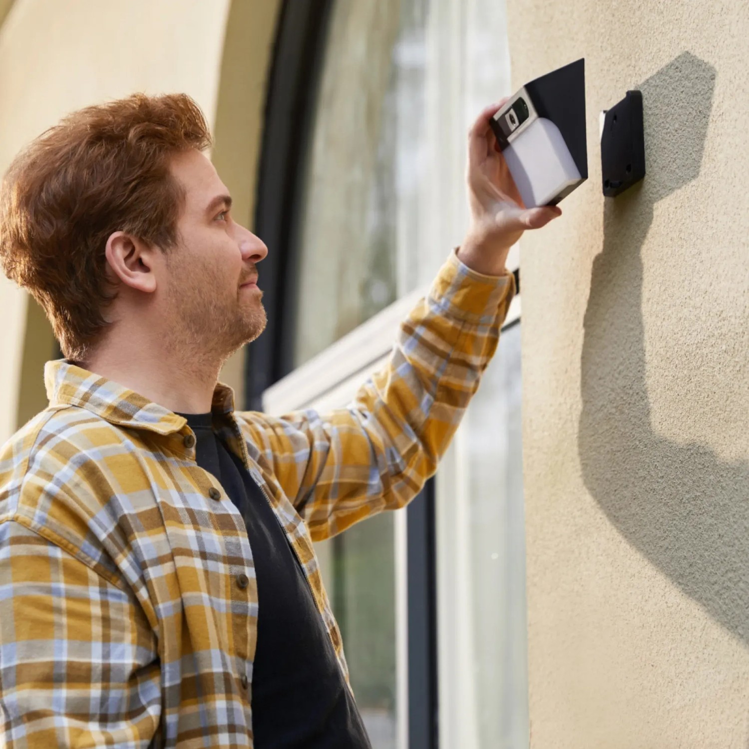 Mann montiert Eufy Solar-Wandleuchte mit Kamera S120 KI 2K an Hauswand.