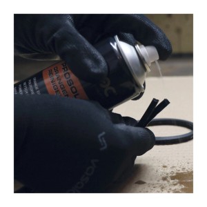 Hand in Handschuh sprüht Staloc Orangenreiniger auf schwarze Teile. Reinigungsmittel Set zur Entfettung von Ketten, Kunststoff, Alu.
