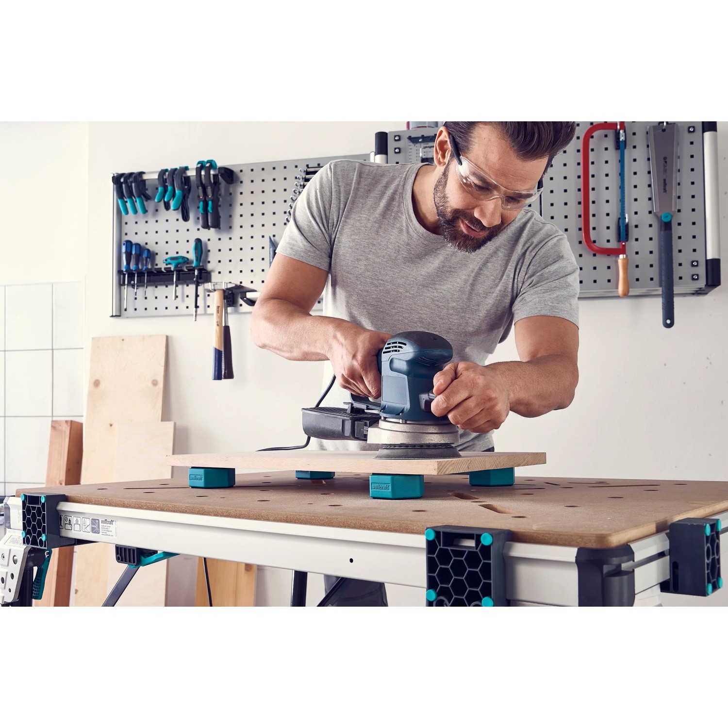 Mann schleift Holz auf Werkbank mit wolfcraft Werkstückauflagen-Set (4 Stück) als Unterlage.