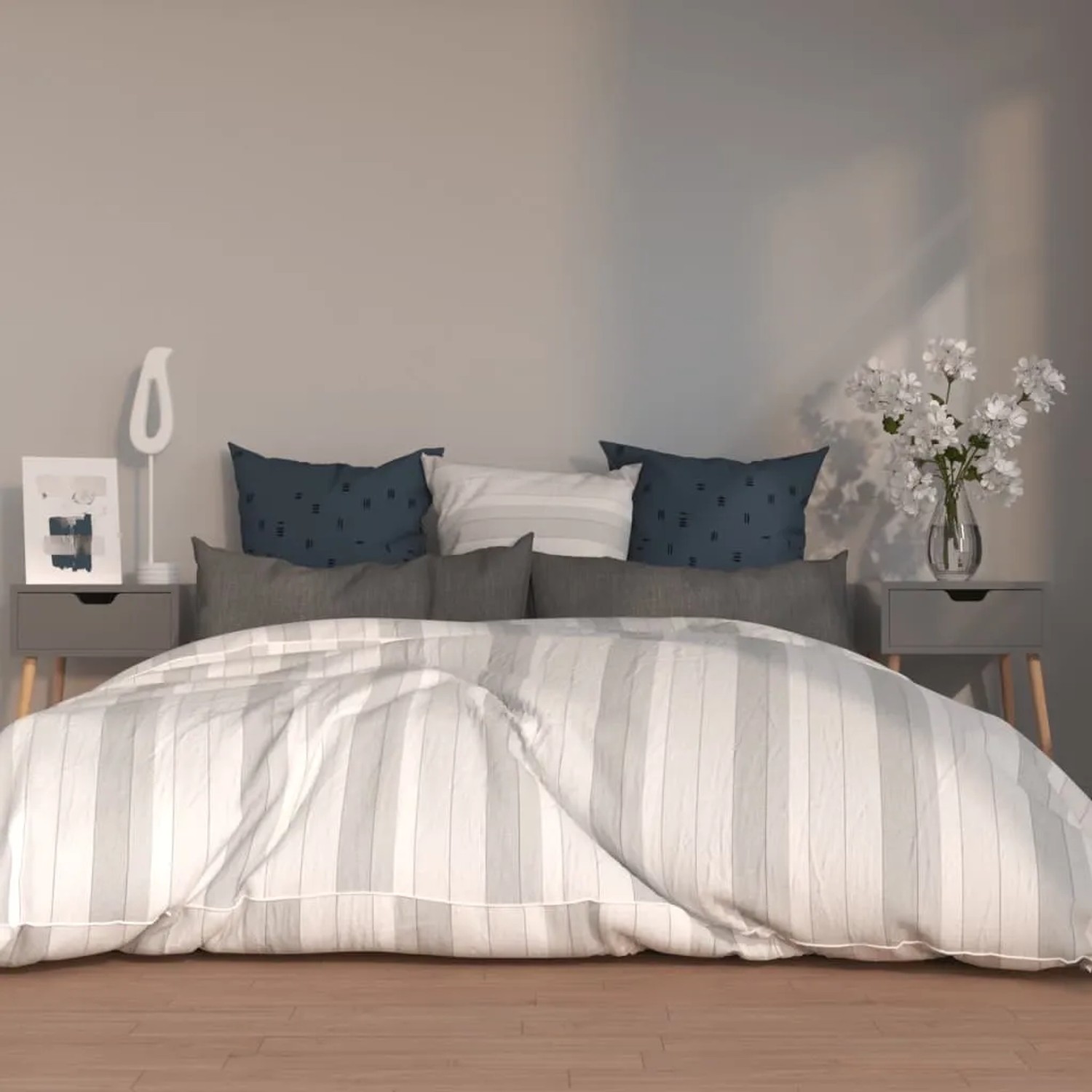 Zwei graue Nachttische aus Holzwerkstoff neben einem Bett mit Kissen und Dekoration.