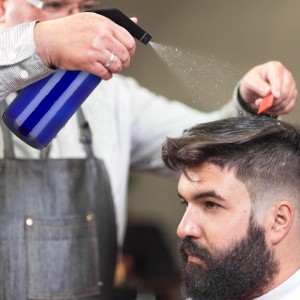 Relaxdays Sprühflasche 2er Set Blau: Friseur befeuchtet Haare mit der Glas Sprühflasche.