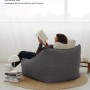 Grauer mokebo Cord Sitzsack Sessel "Der Lümmel" mit Hocker und lesendem Mann im Wohnzimmer.