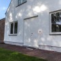 Quadratische LED Hausnummernleuchte Alice mit Ziffern auf weißer Hauswand.