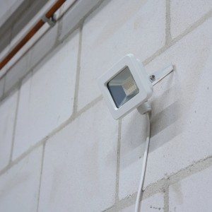 Weißer LED-Außenstrahler (10W, 1100lm, 4000K) an einer Wand montiert.