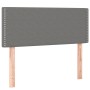 Boxspringbett Kopfteil, dunkelgrauer Stoff mit Ziernägeln, Holzfüße.