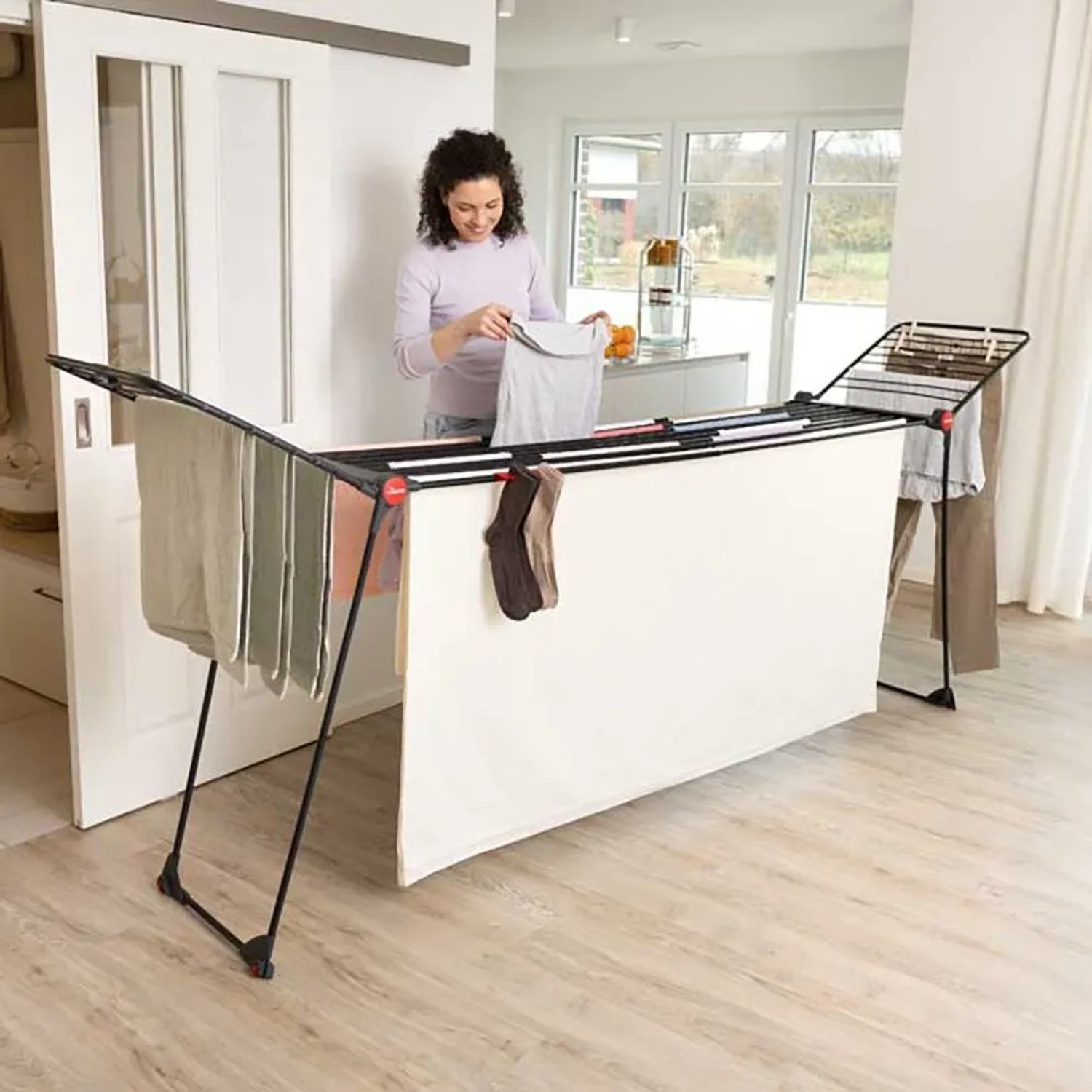 Vileda Wäscheständer Infinity Flex Ultimate, schwarz, mit Wäsche behangen und Frau beim Wäsche aufhängen.