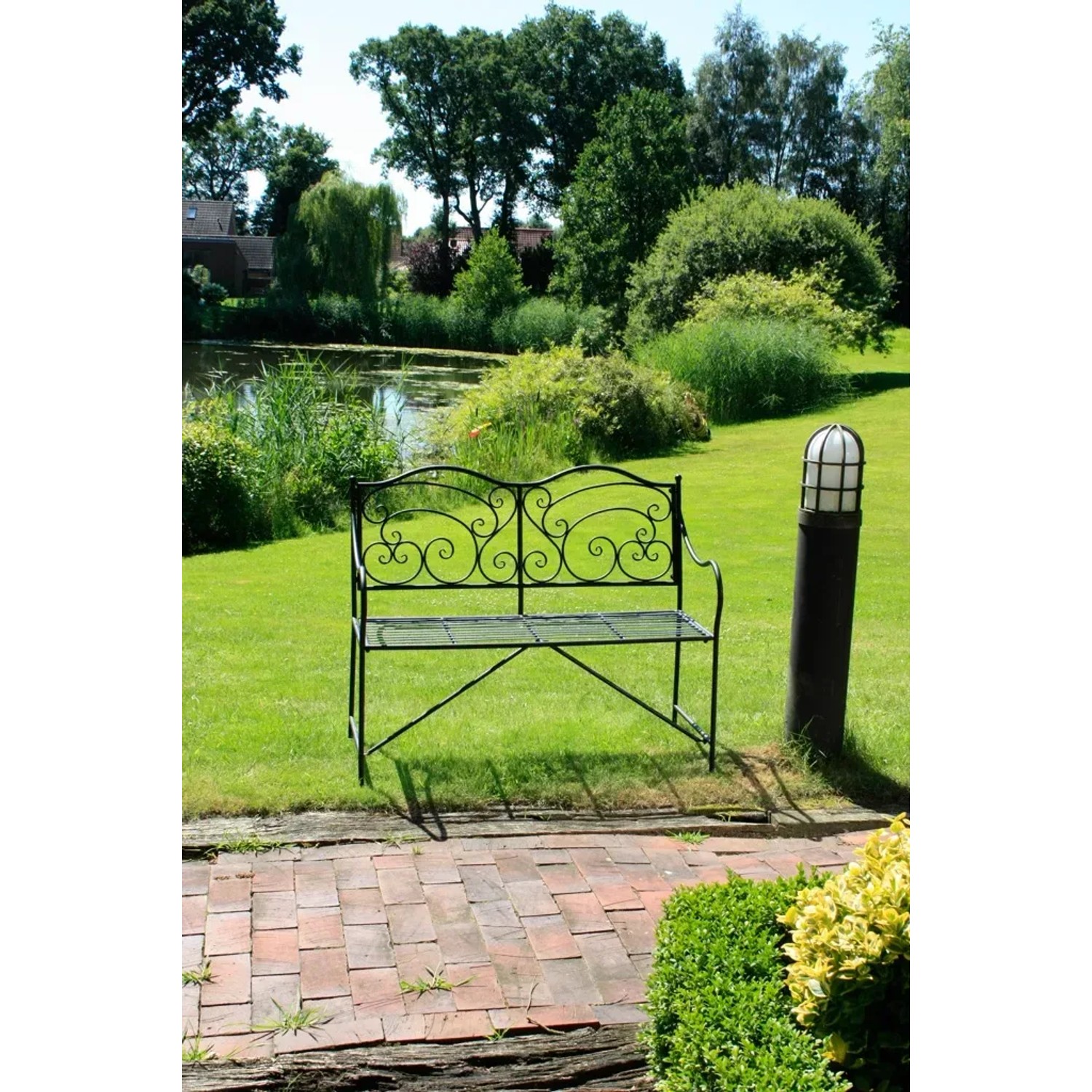 Schwarze Garden Pleasure Gartenbank Vesuv mit verzierter Lehne im Garten.