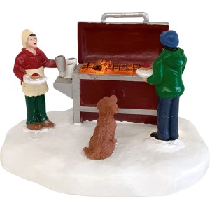 Weihnachtsdorf Figur: Grill-Camping Szene mit zwei Personen und Hund im Schnee. Detailreiche Weihnachtsdekoration.
