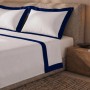 Weißes Baumwoll-Bettwäsche-Set für Einzelbett mit blauer Satin-Bordüre auf Laken und Kissenbezug.