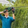 Mann schneidet Hecke mit Bosch Akku-Heckenschere Universal Hedge Cut 18-55.