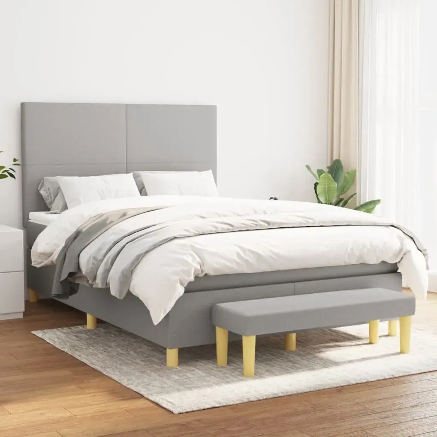 Hellgraues Boxspringbett mit Matratze und Bank, Stoffbezug. Modernes Design für Schlafzimmer.