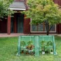 Grünes WOLTU Foliengewächshaus mit Metallrahmen, gefüllt mit Pflanzen, auf Rasen im Garten. Ideal für Anzucht & Schutz.