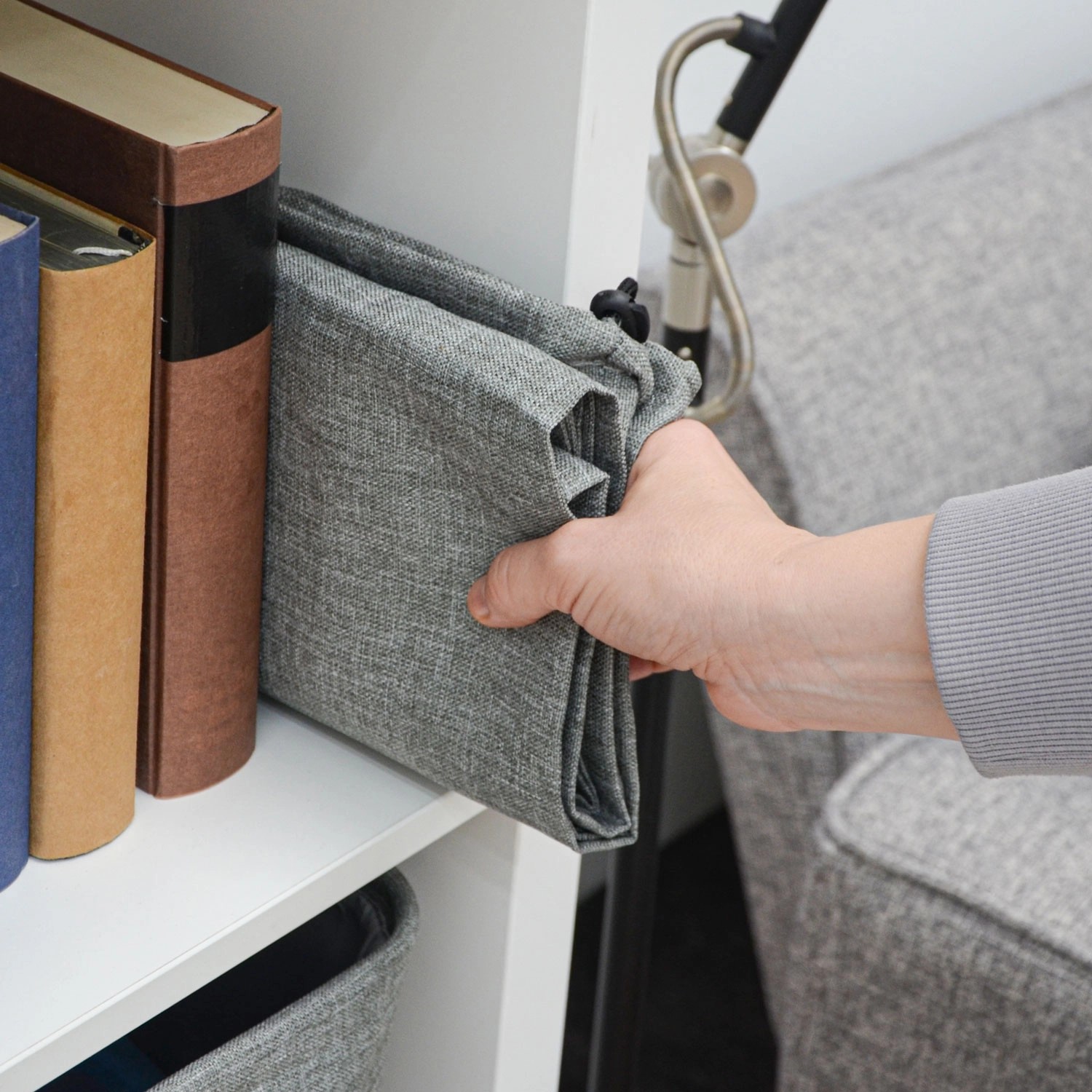 Zusammengefalteter, grauer DuneDesign Wäschesack (100L/60L) im Regal, Teil eines Wäschesammler Sets.