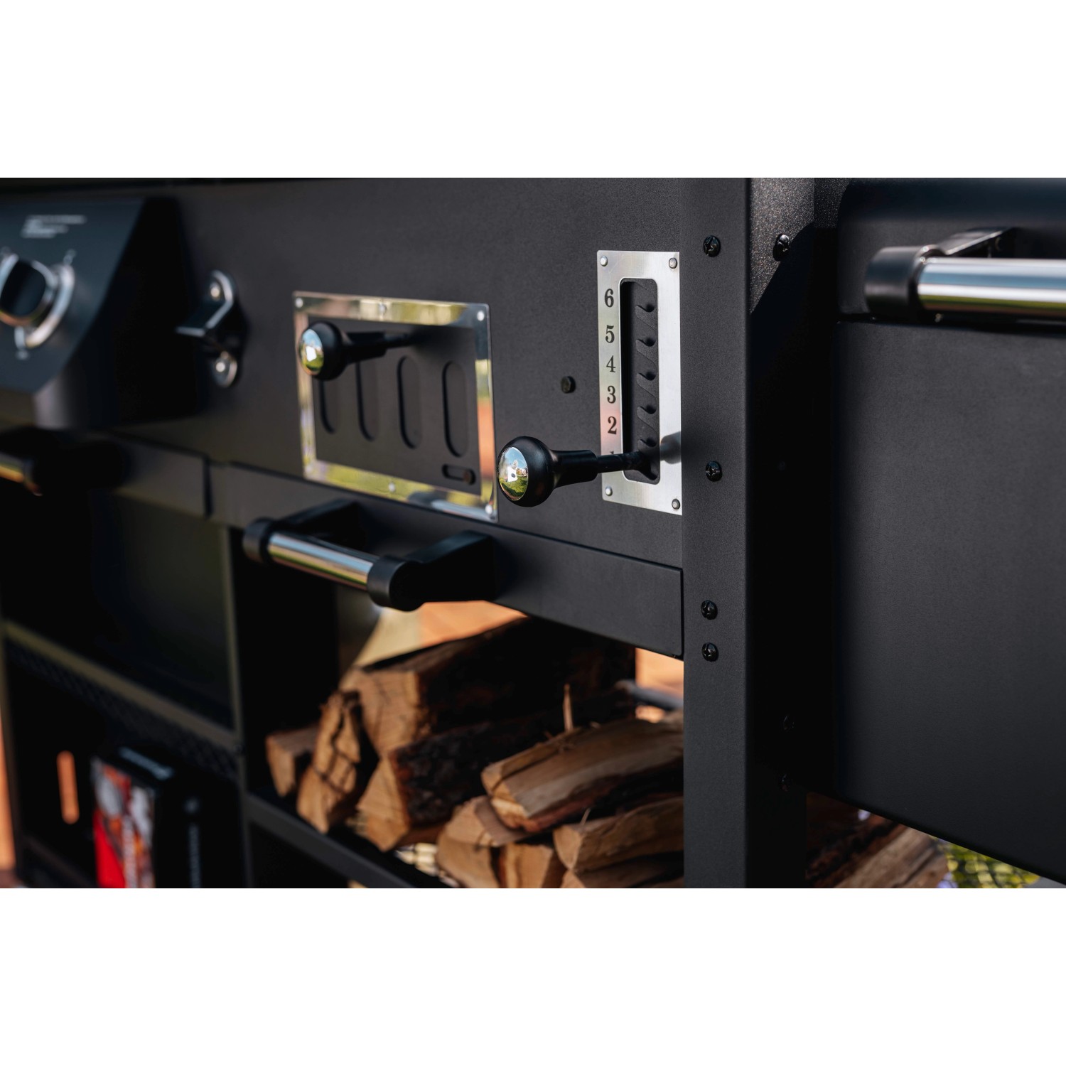 Detailaufnahme des Jamestown Kombigrill Drake: Bedienelemente und Holzscheite im Ablagefach.