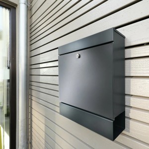 Anthrazitfarbener Burg-Wächter Briefkasten Seattle 848 mit Zeitungsbox an einer Holzwand.