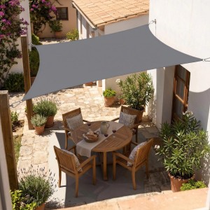 Rechteckiges anthrazitfarbenes Sonnensegel aus Polyester über einer Terrasse, bietet UV-Schutz und Schatten für Gartenmöbel.